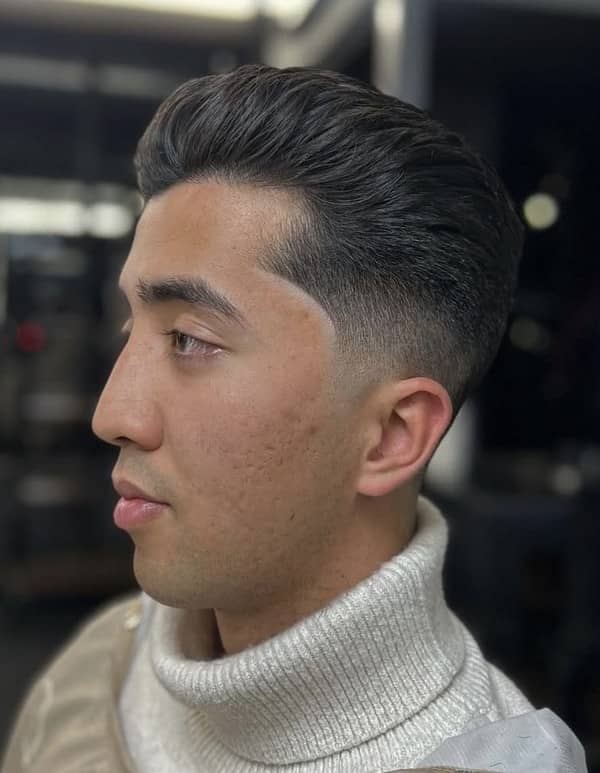 Side profile of a man with a comb-over fade haircut, styled neatly by Clipper Cole barber in Charlotte, NC